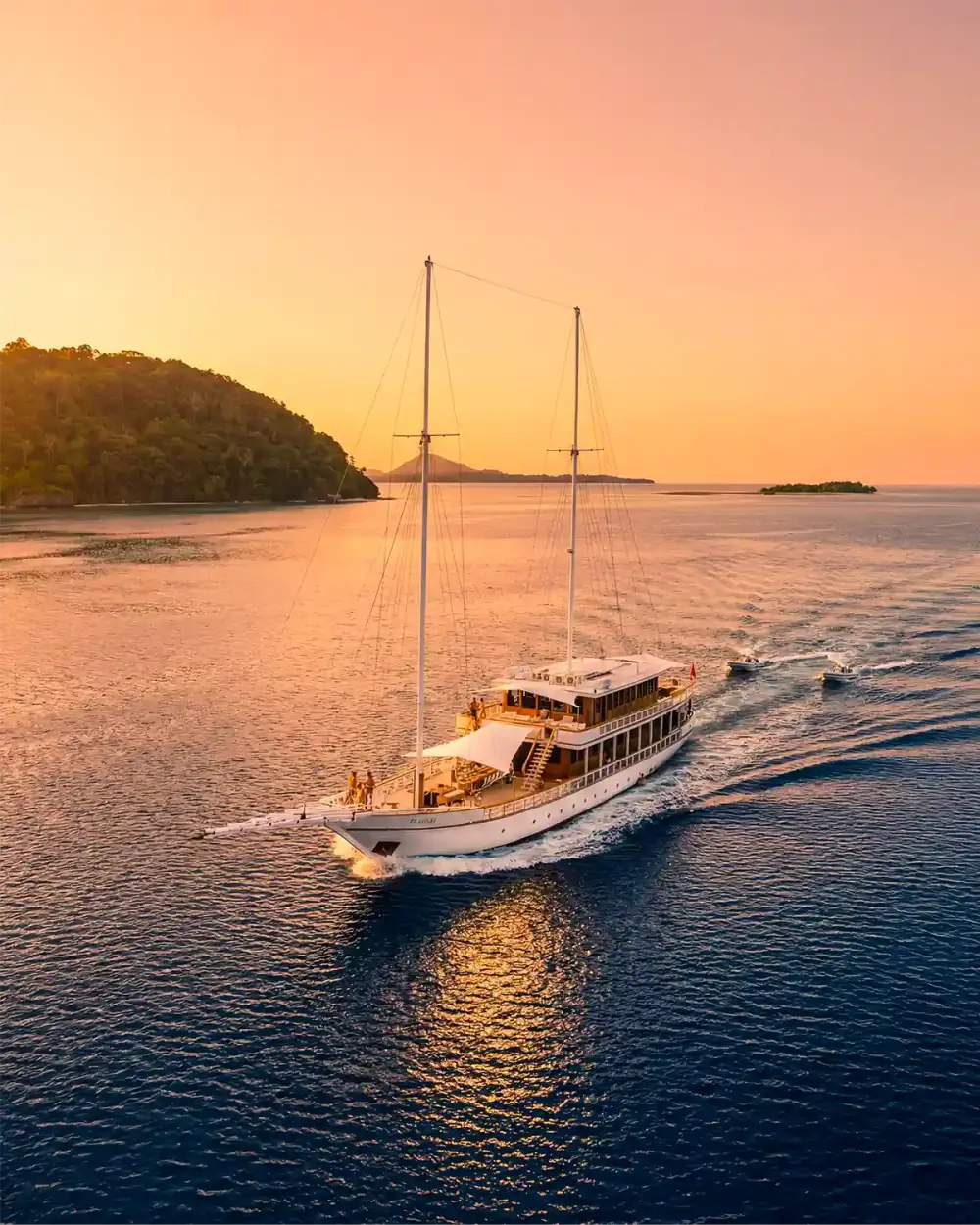 Twin-masted vessel underway at golden hour