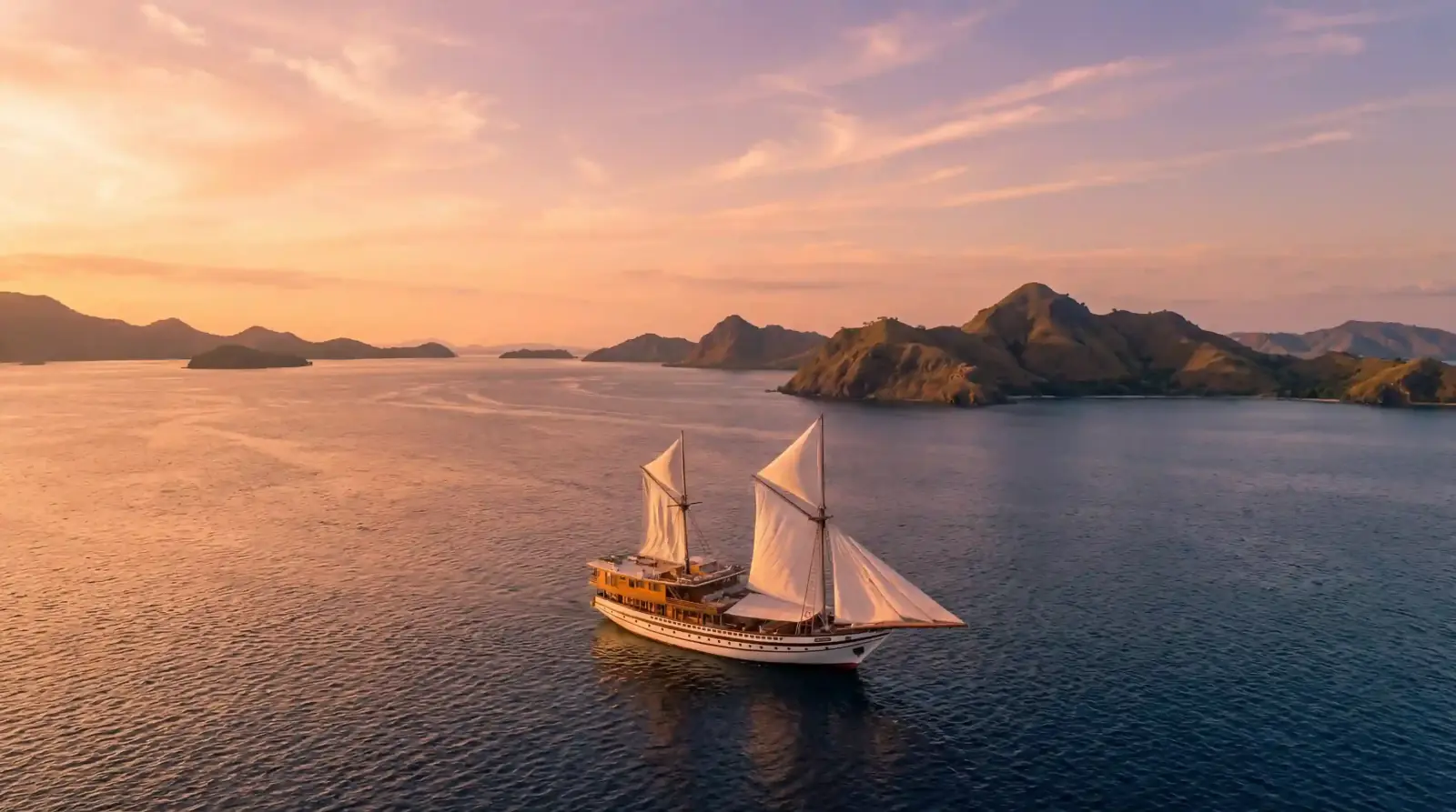 Phinisi sailing past the hills of Komodo at sunset
