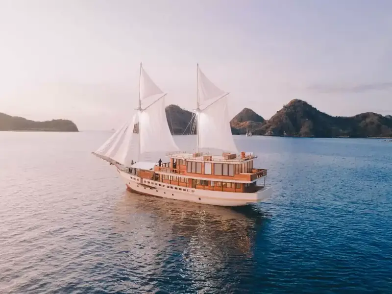 Phinisi sailing past island peaks