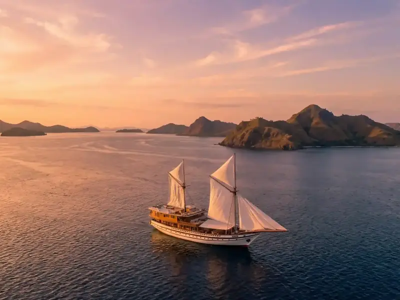 Phinisi under sail at sunset in Komodo