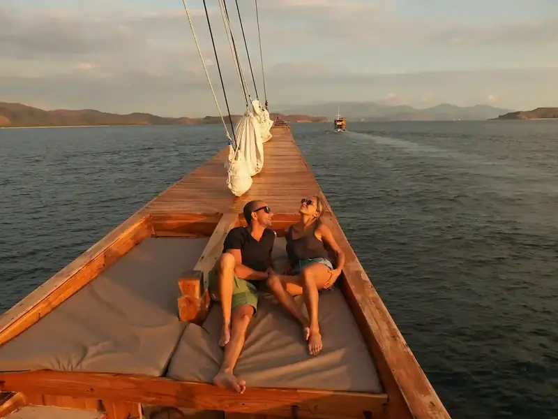 Couple relaxing on a phinisi bow at sunset