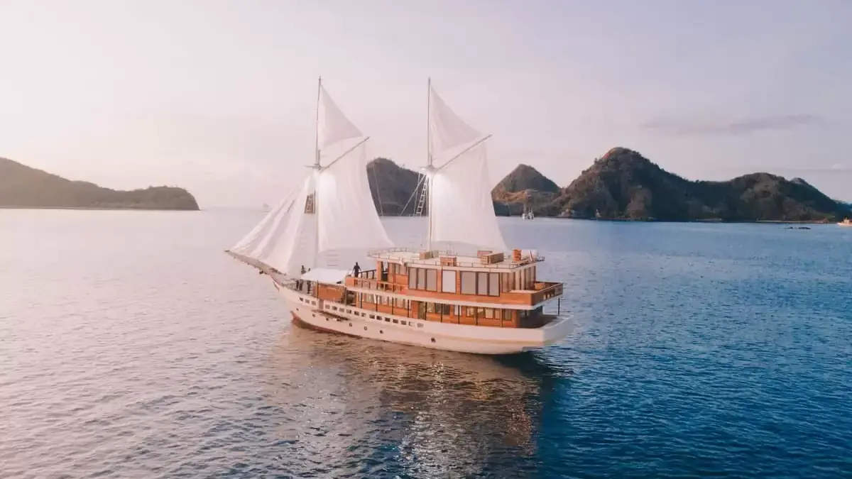 Phinisi sailing past steep island peaks