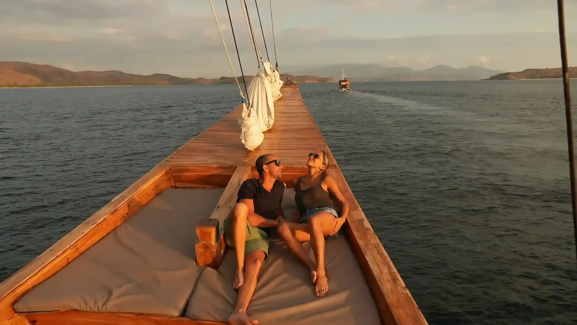 Couple relaxing on the bow of a phinisi at sunset