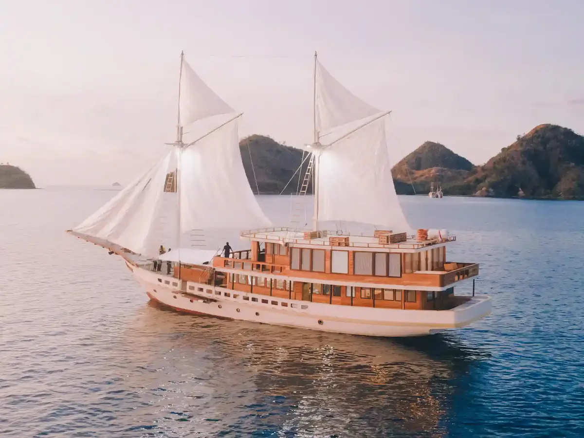 Phinisi under full sail off the hills of Komodo